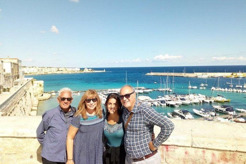 A group of people standing on a stone wall overlooking a marina with boats. 2