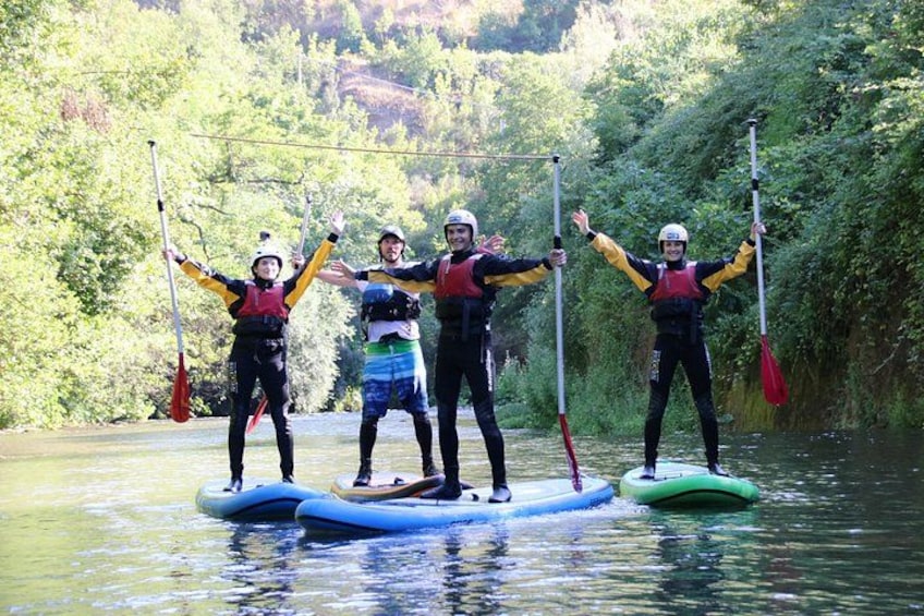 Menschen paddeln auf Stand-Up-Boards in einem von Grün umgebenen Fluss. 3