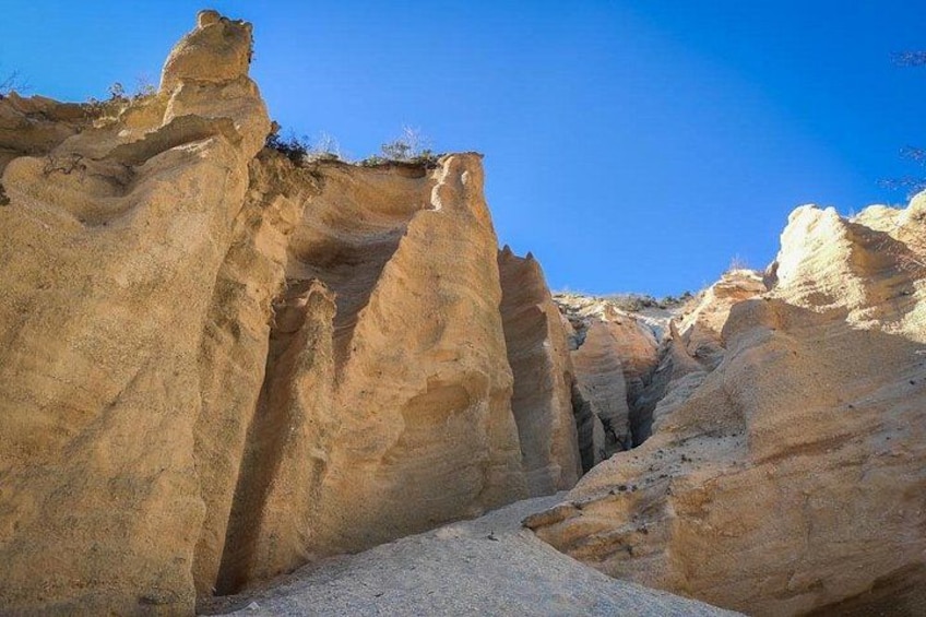 A rocky canyon with steep cliffs and a clear blue sky. 3