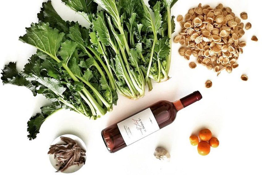 Una bottiglia di vino, verdure a foglia verde, noci e agrumi su sfondo bianco. 1