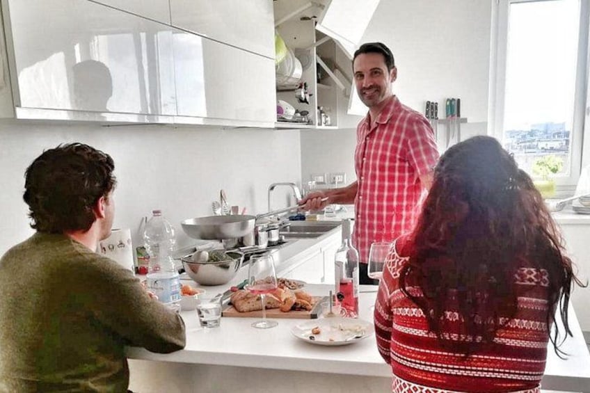 A modern kitchen with white cabinets, a stainless steel countertop, and a person cooking. 1