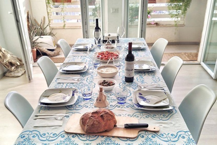 Una tavola imbandita con piatti, ciotole, pane, una bottiglia di vino e posate. 3