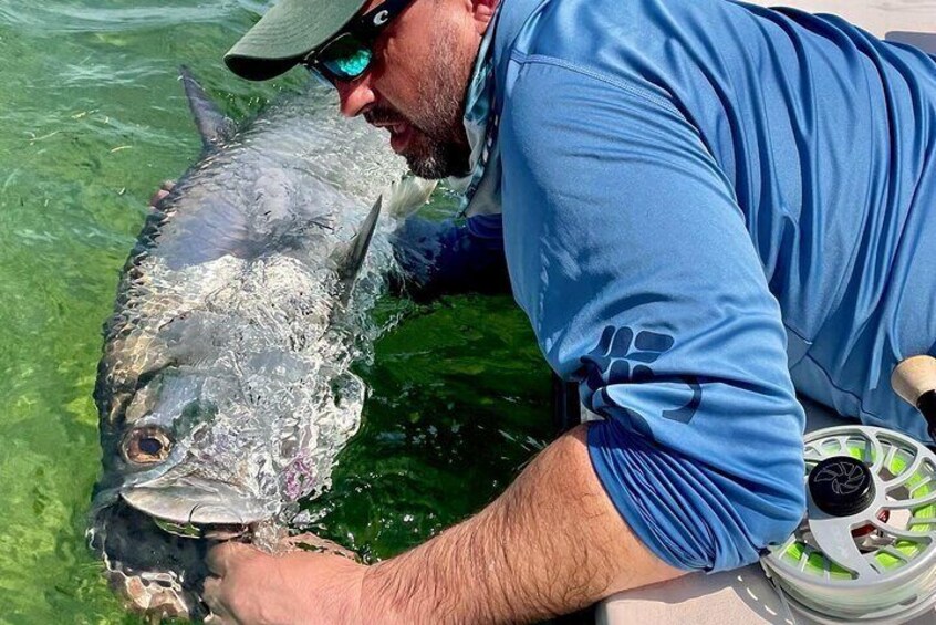 A person holding a large fish in clear water. 2