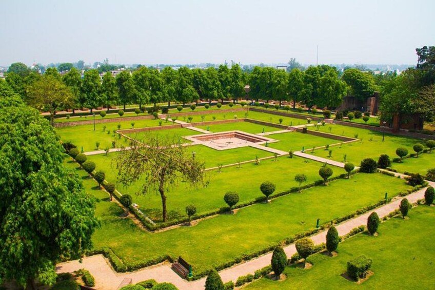 Un parque bien cuidado con senderos geométricos, setos recortados y una plaza central. 2