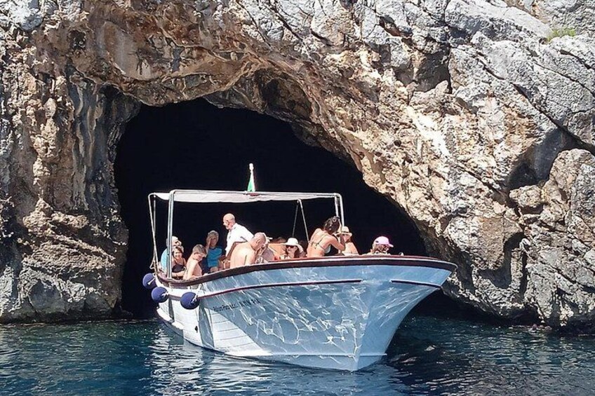 A boat with passengers near a rocky cave entrance. 5