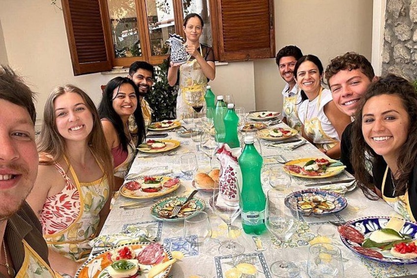 A group of people seated around a table with various dishes and drinks. 3