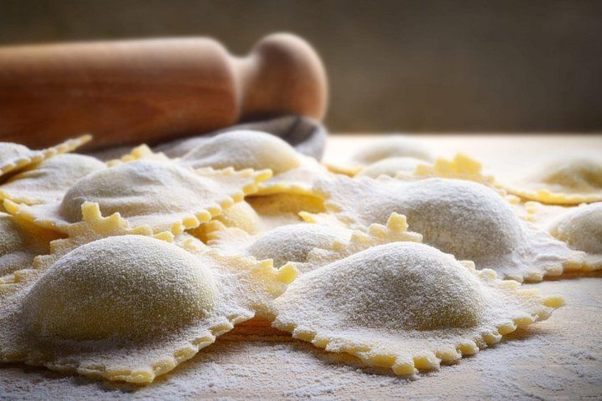 Ravioli on a wooden surface with a rolling pin in the background. 1