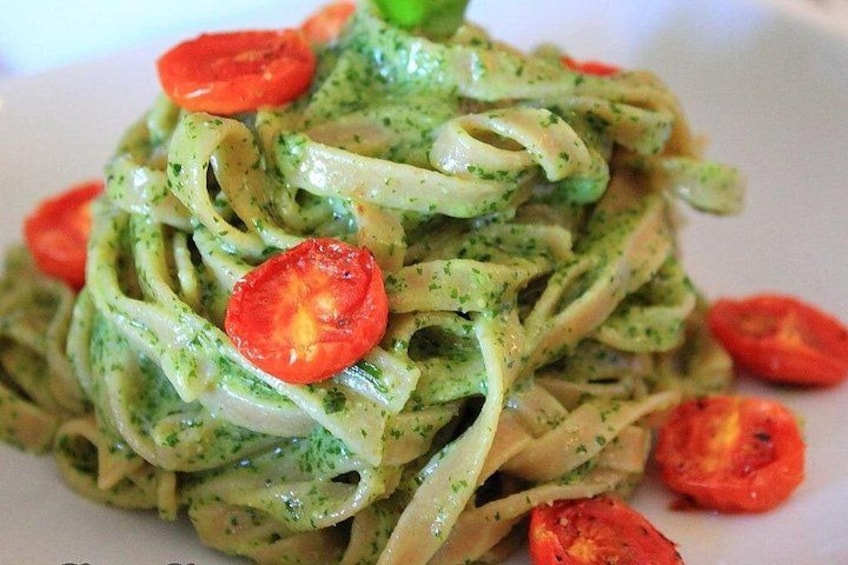 Une assiette de pâtes nappées d’une sauce verte, garnie de tranches de tomates. 4
