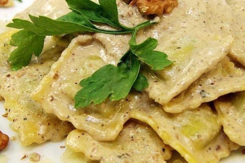 A plate of ravioli with a creamy sauce and garnished with parsley. 2