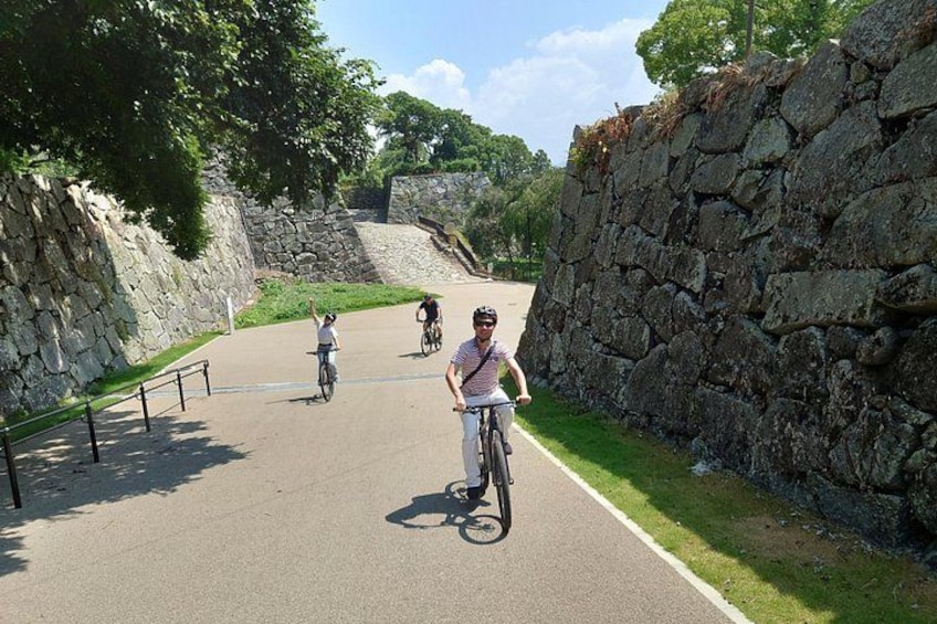 Un sendero pavimentado con ciclistas, muros de piedra y vegetación. 3