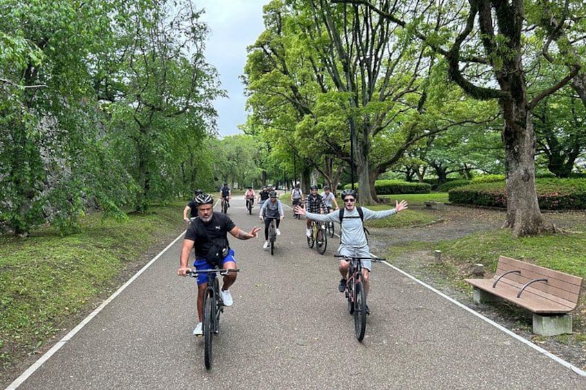 Un sendero pavimentado con ciclistas, rodeado de árboles y un banco. 5