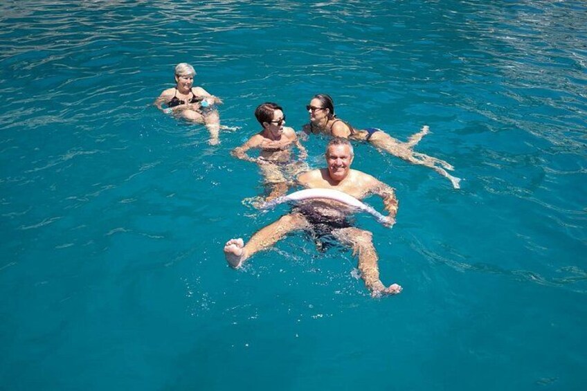 Un grupo de personas flotando en una piscina azul cristalina, algunas sosteniendo tablas de surf. 4