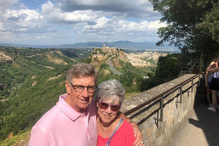 Ein Paar steht auf einer Aussichtsplattform mit einer historischen Burg im Hintergrund. 1