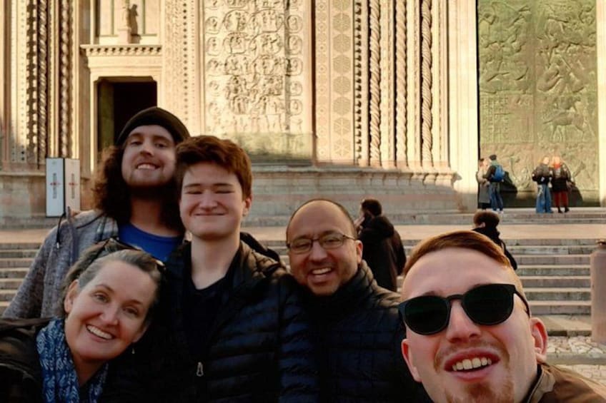 A group of people in front of a building with detailed carvings and a large door. 2