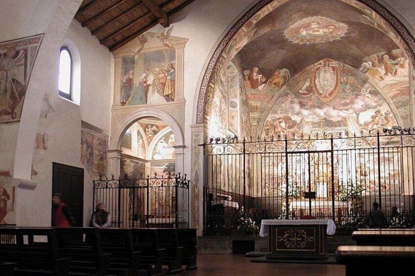 An interior of a church with arched ceilings, frescoes, and a central altar. 4