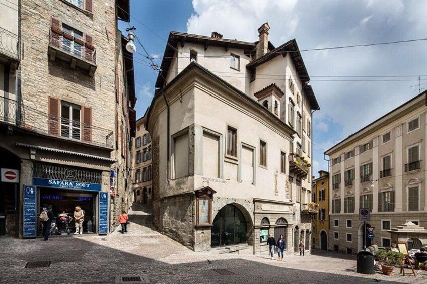 A street with historic buildings, a café, and pedestrians. 2