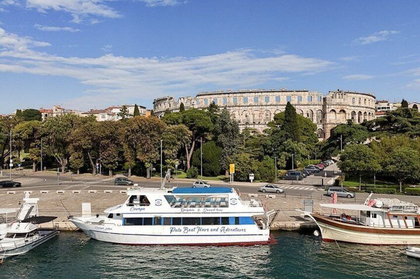 A waterfront with a large white boat docked, a historic building in the background, and a clear blue sky. 5