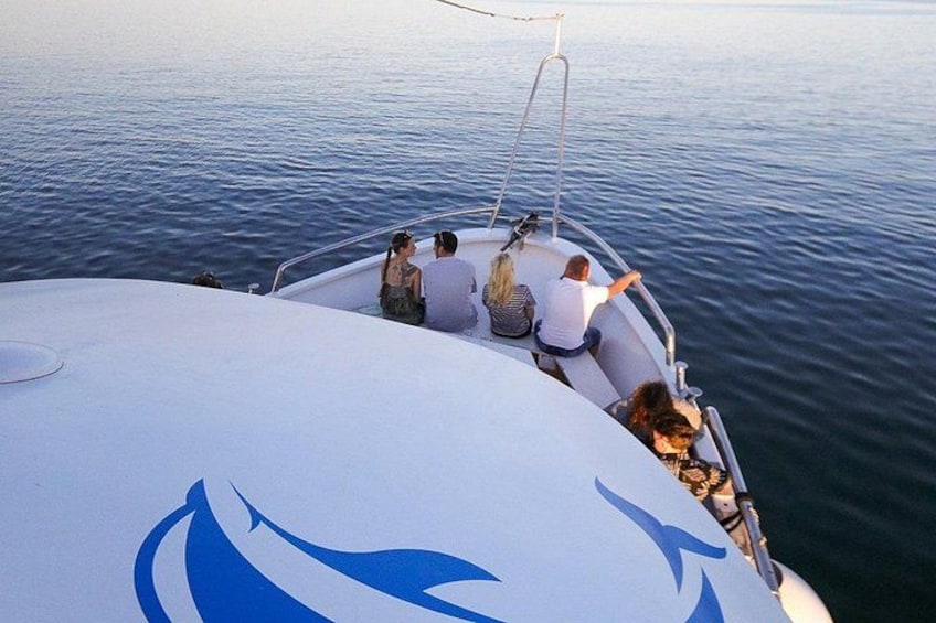 A boat with people on board, calm water, and a clear sky. 2
