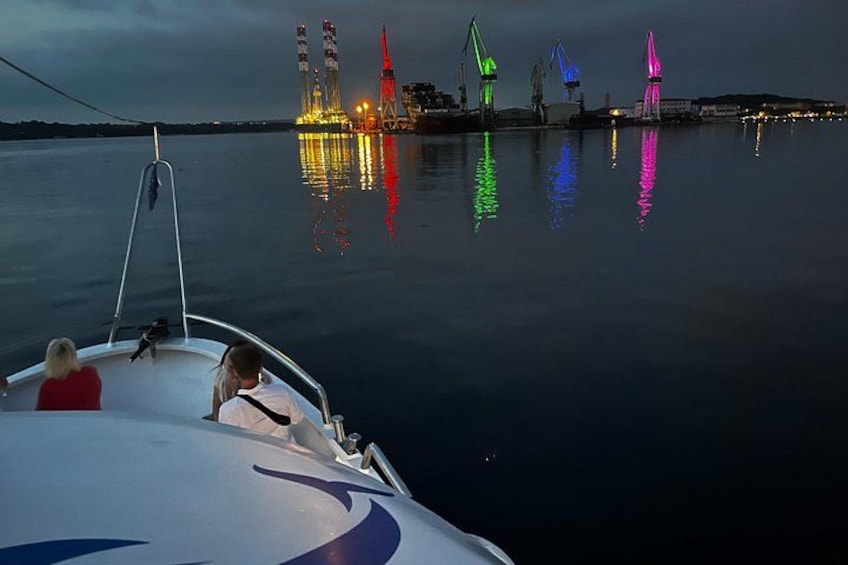 A boat on calm water with a city skyline in the background, illuminated by colorful lights. 4