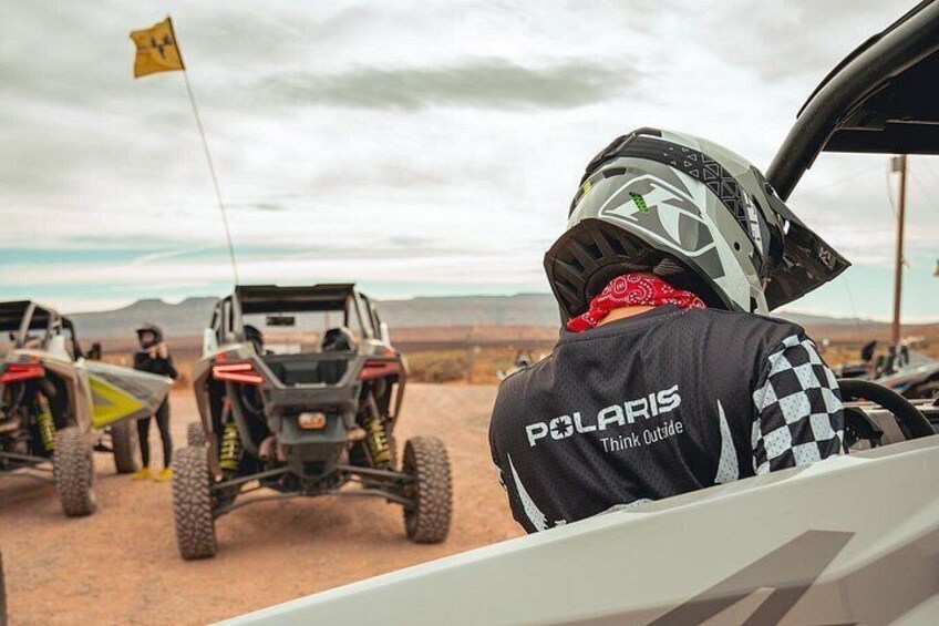 A person in a Polaris vehicle with a desert landscape in the background. 2