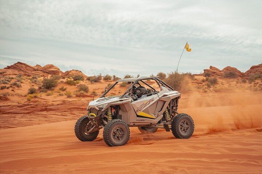 A Polaris off-road vehicle driving through a desert landscape. 3