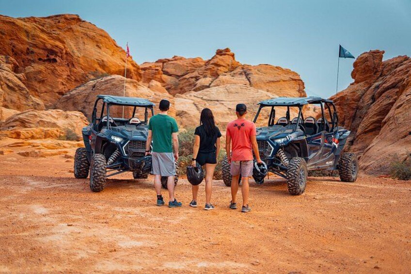 Three off-road vehicles parked on a dirt path with red rock formations in the background. 5