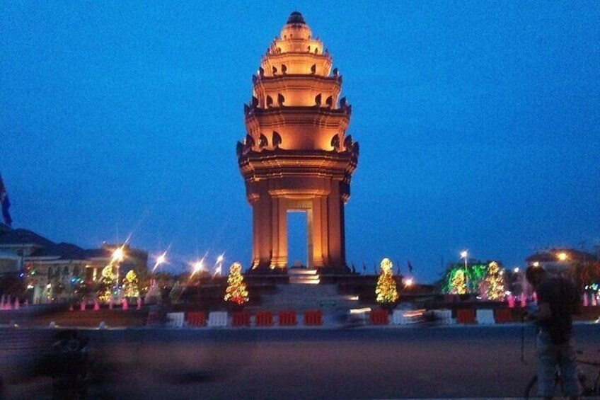 A large, illuminated tower with a dome and columns, surrounded by trees and lights. 4