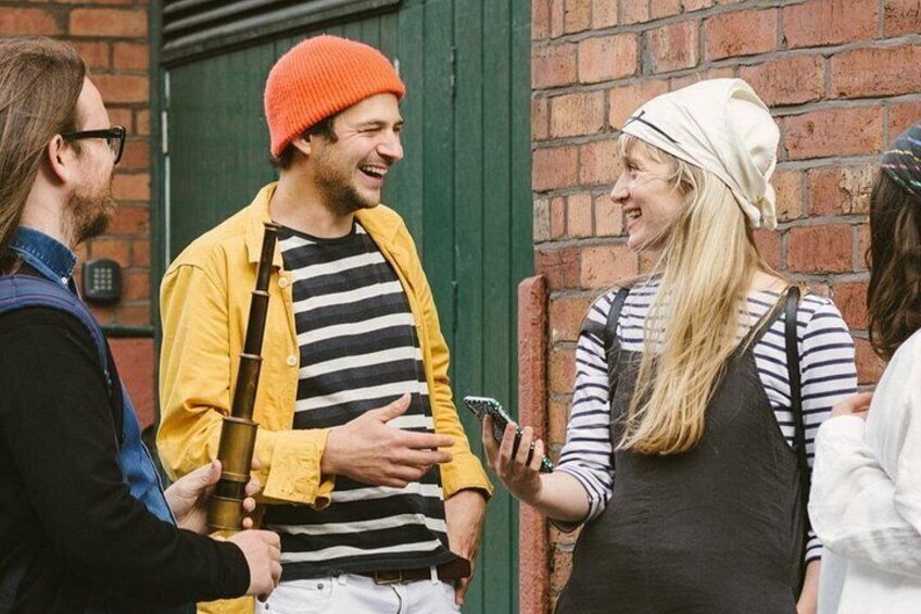 A group of people standing outdoors near a brick wall with a green door. 2