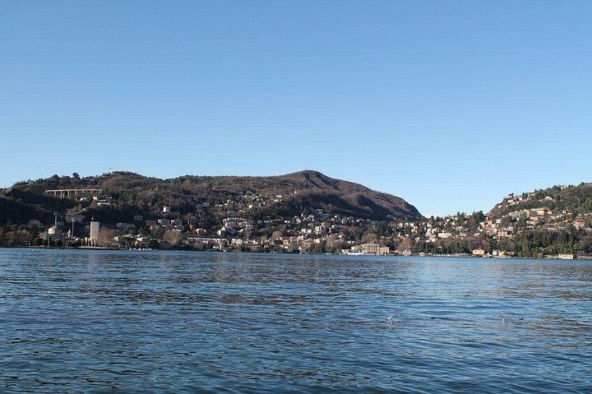 Un lago tranquilo con un pueblo en la orilla opuesta, rodeado de colinas. 2