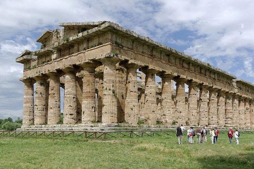 Ein antiker griechischer Tempel mit Säulen und Besuchern im Vordergrund. 1