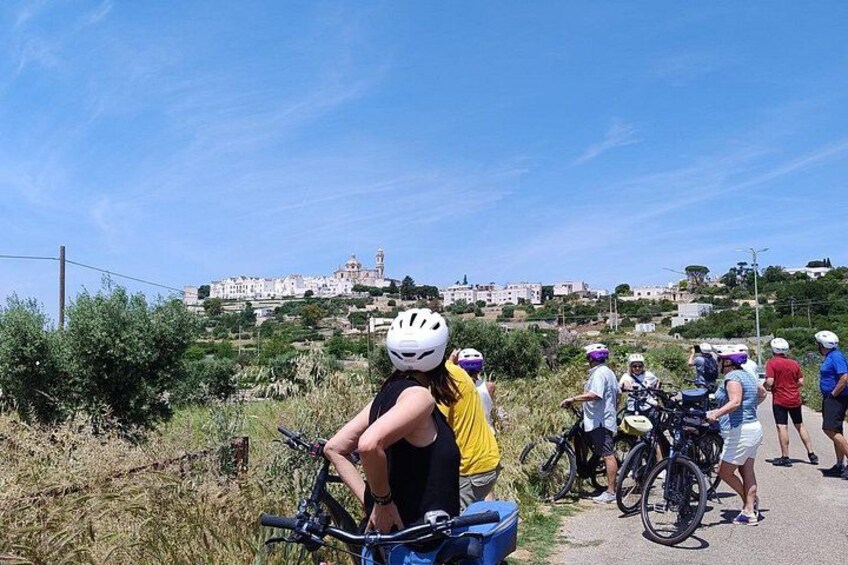 A group of cyclists on a path with a town in the background. 3