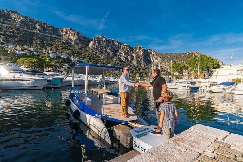 A docked boat with a solar panel, a rocky coastline, and boats in the background. 2