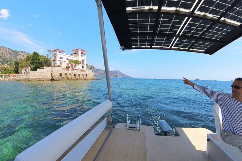 Un bateau avec une personne à bord qui pointe vers un bâtiment situé sur la côte. 2