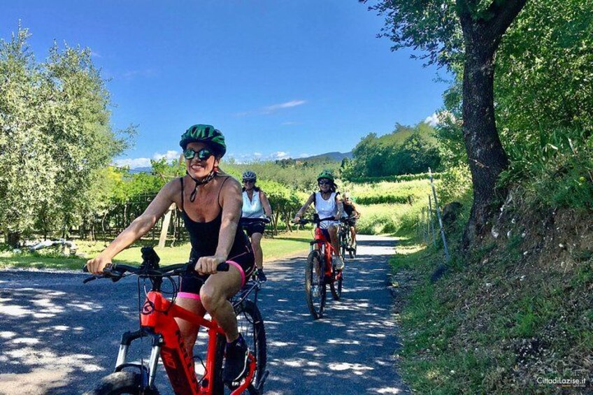 Trois cyclistes sur une piste cyclable asphaltée, entourés de verdure. 1