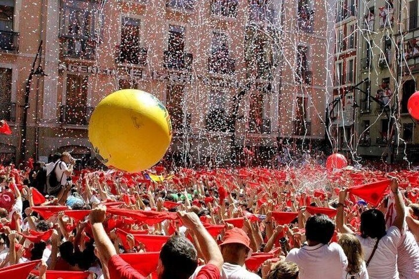 A crowd of people in red shirts, confetti, and a yellow ball. 2