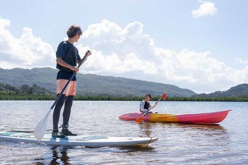 Two people paddleboarding on a lake with mountains in the background. 2