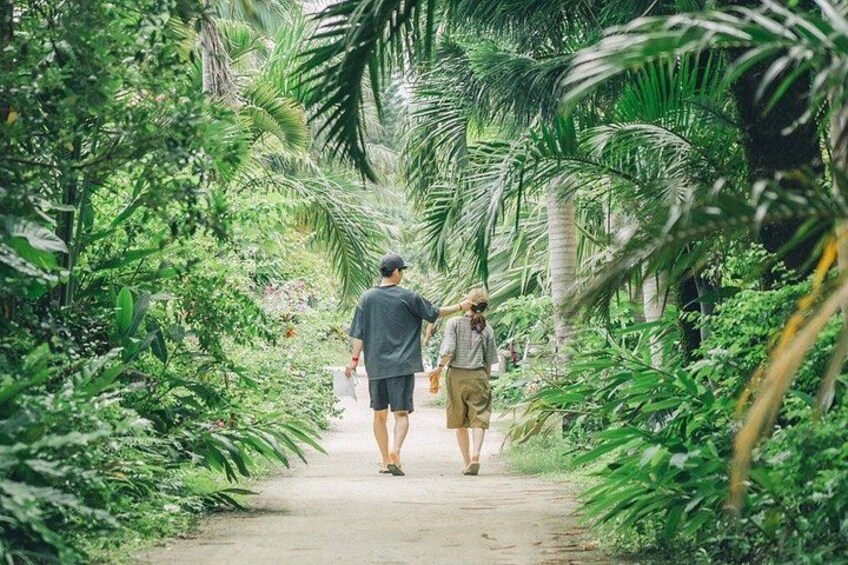 Two people walking on a path surrounded by lush greenery. 2
