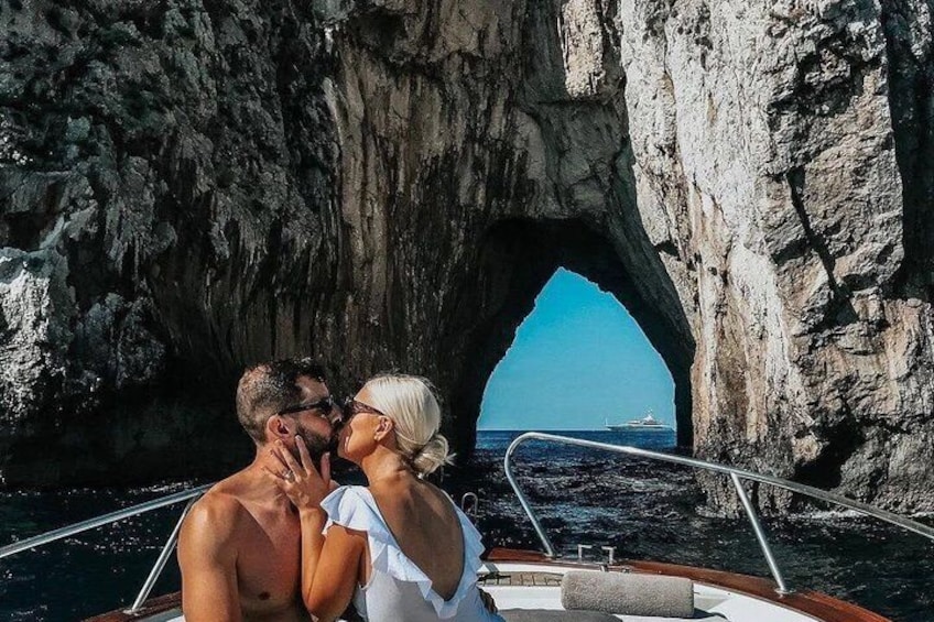 A couple kissing in front of a rocky arch on a boat. 2