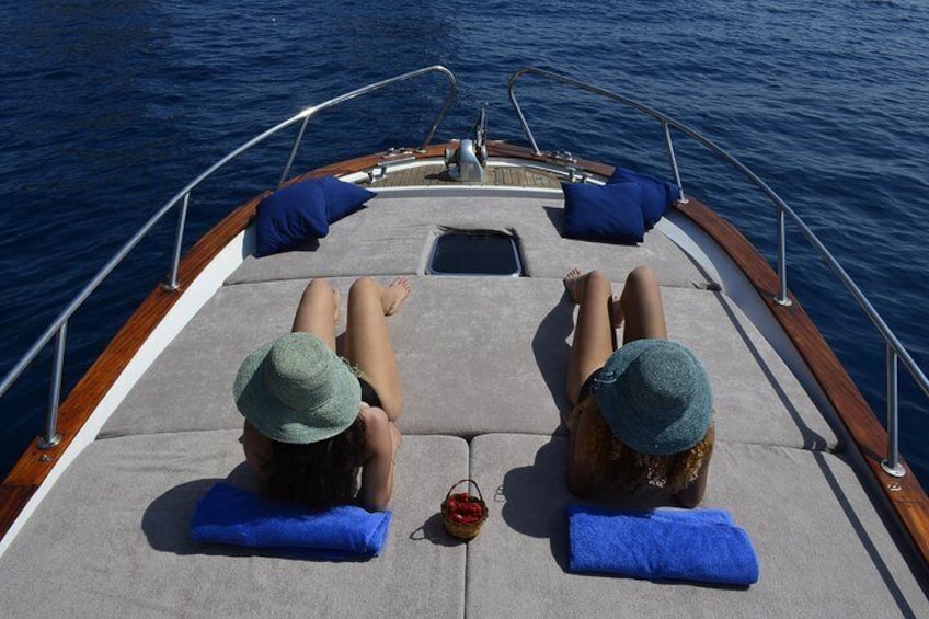 Two people relaxing on a boat deck with blue towels and a small red item. 5