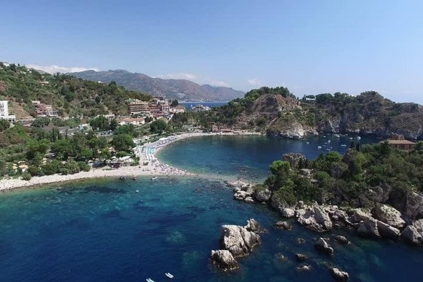 A coastal landscape with a beach, rocky outcrops, and a clear blue sea. 3