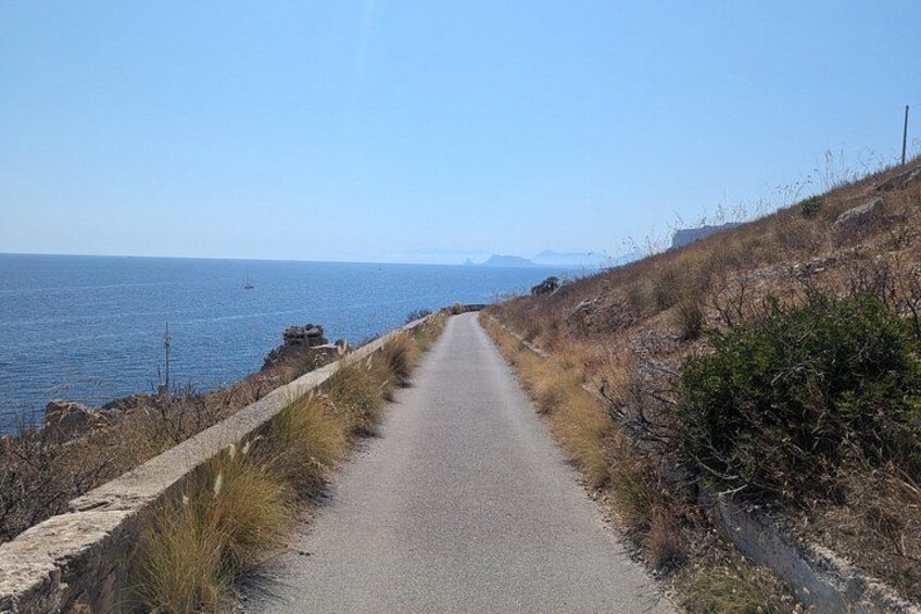A coastal road with a clear view of the ocean and distant mountains. 5