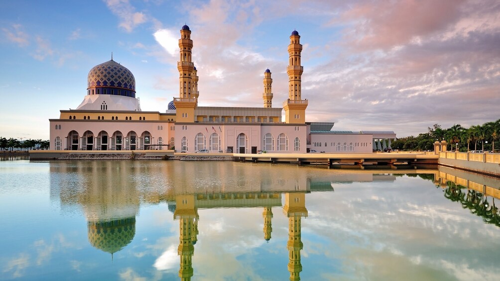 A mosque with a large dome and two minarets, reflecting in a calm body of water. 1