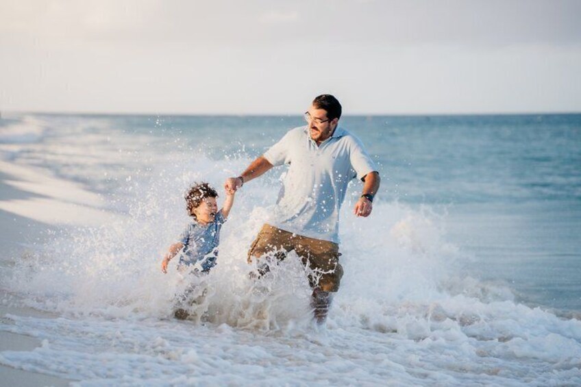 A man and a child playing in the ocean waves. 4