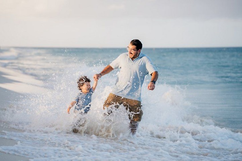 A man and a child playing in the ocean waves. 2