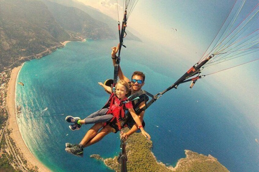 A person paragliding over a coastal landscape with a beach and mountains in the background. 4