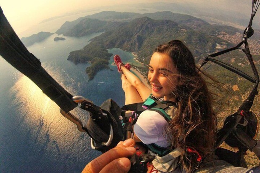 A person skydiving with a parachute, overlooking a coastal landscape with mountains and a body of water. 1