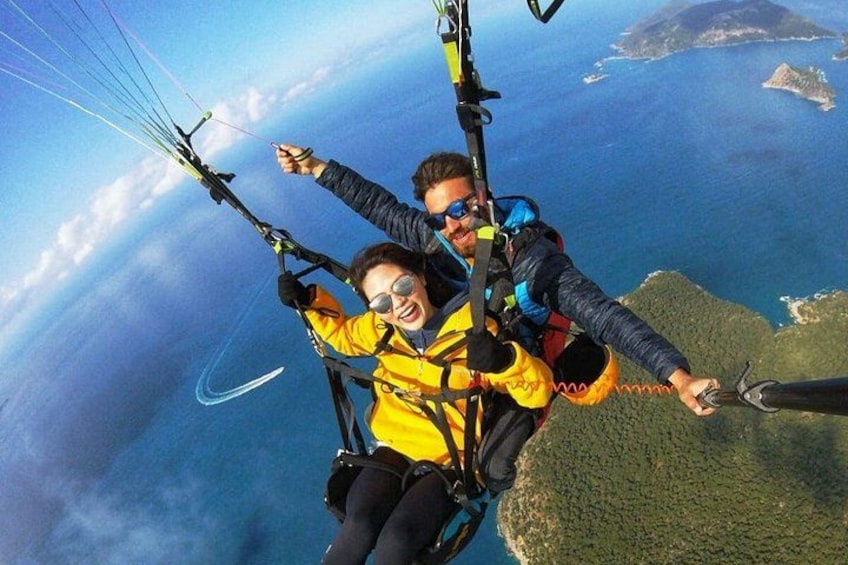 Twee mensen paragliden boven een kustlandschap, met daaronder land te zien. 2