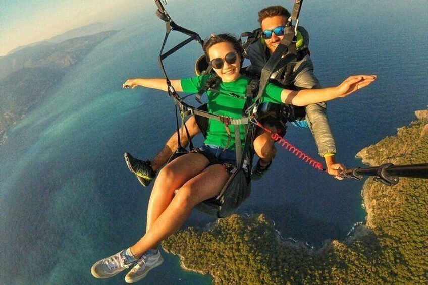 Two people skydiving with a parachute, overlooking a coastal landscape. 5