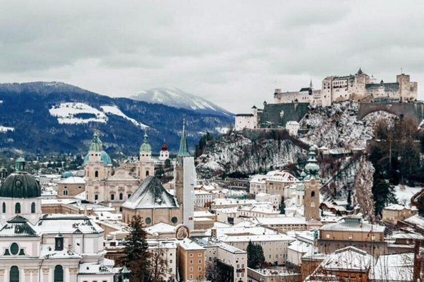 A snow-covered cityscape with historic buildings and a castle on a hill. 2
