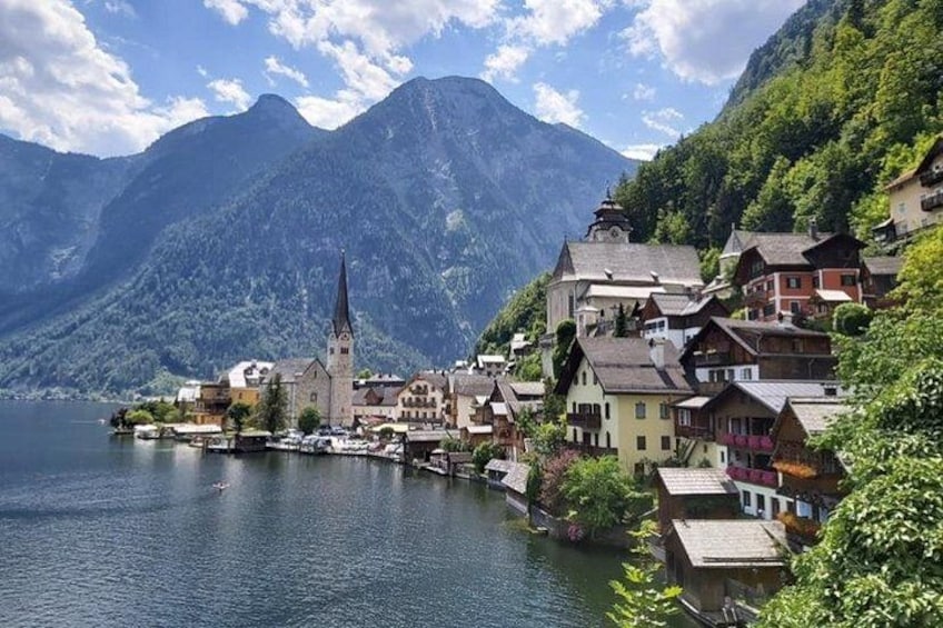 Un village au bord d’un lac, avec des maisons traditionnelles, une église et des montagnes en arrière-plan. 4